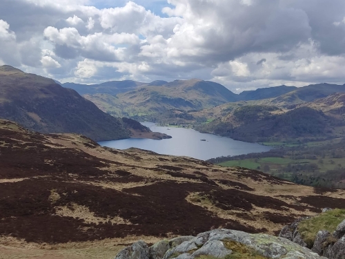 The bracken, heather and rocks of the top of Gowbarrow in the foreground, the curve of 
                                Ullswater in the midground and numerous fells in the distance